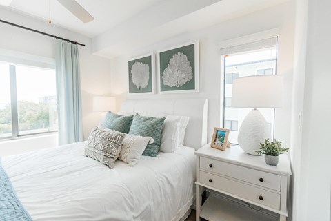 a bedroom with a bed with pillows and a dresser with a lamp and