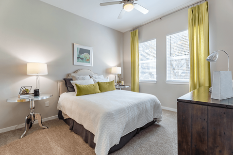 A bedroom with a bed, nightstand, and window.