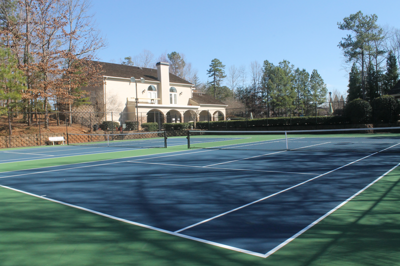 a tennis court with a house in the background