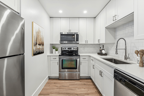 A modern kitchen with a stainless steel refrigerator and white cabinets.