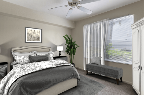 Virtually staged bedroom with tan carpeted flooring, arge window with white blinds and a white multi-speed ceiling fan