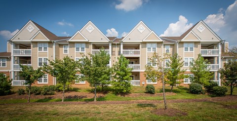 Apartment complex with multiple buildings and green trees in front.