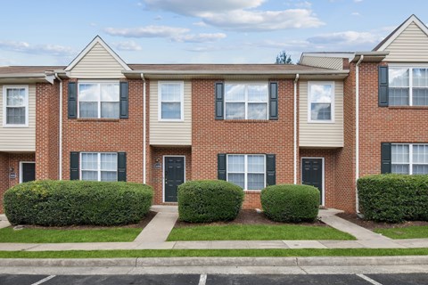A row of townhouses with black shutters and white windows.