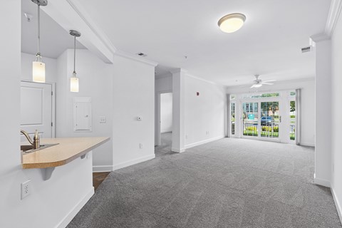 A spacious room with a carpeted floor and a ceiling fan.
