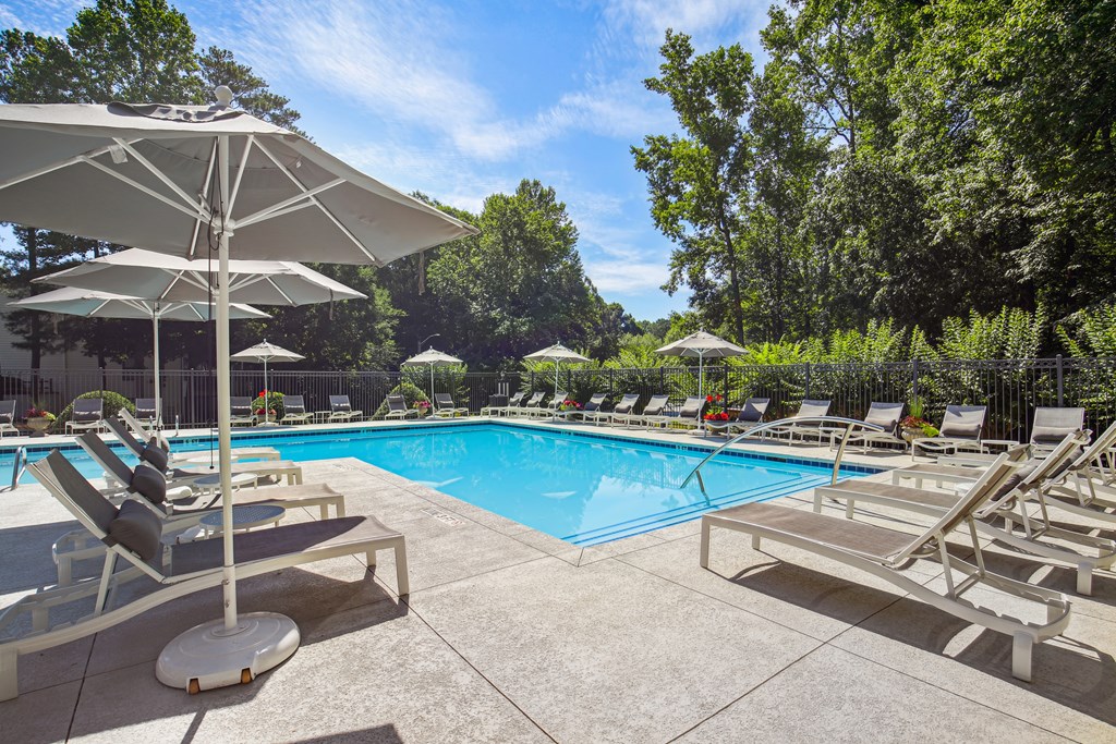 A pool with sun loungers and umbrellas.