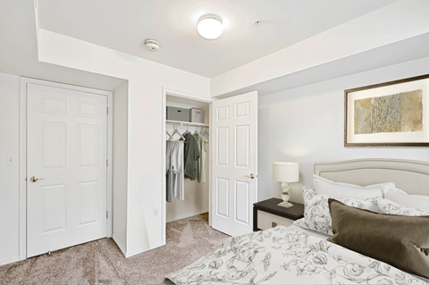 Bedroom with walk-in closet and neutral bedding at Rose Cove Homes Apartments, Farmington, UT