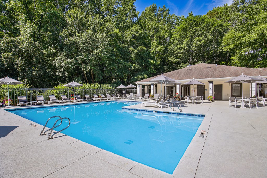 A large swimming pool surrounded by trees and lounge chairs.