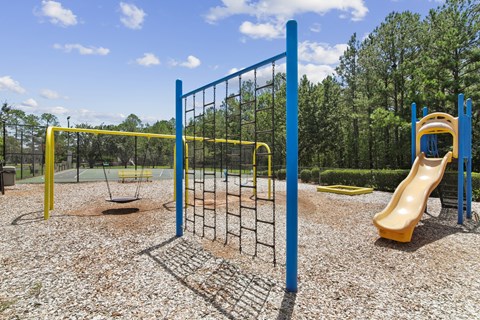 A playground with a yellow slide and a blue fence.
