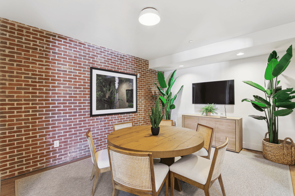 a dining room with a brick wall and a table and chairs