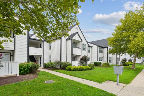 Apartment complex with a white fence and green trees.