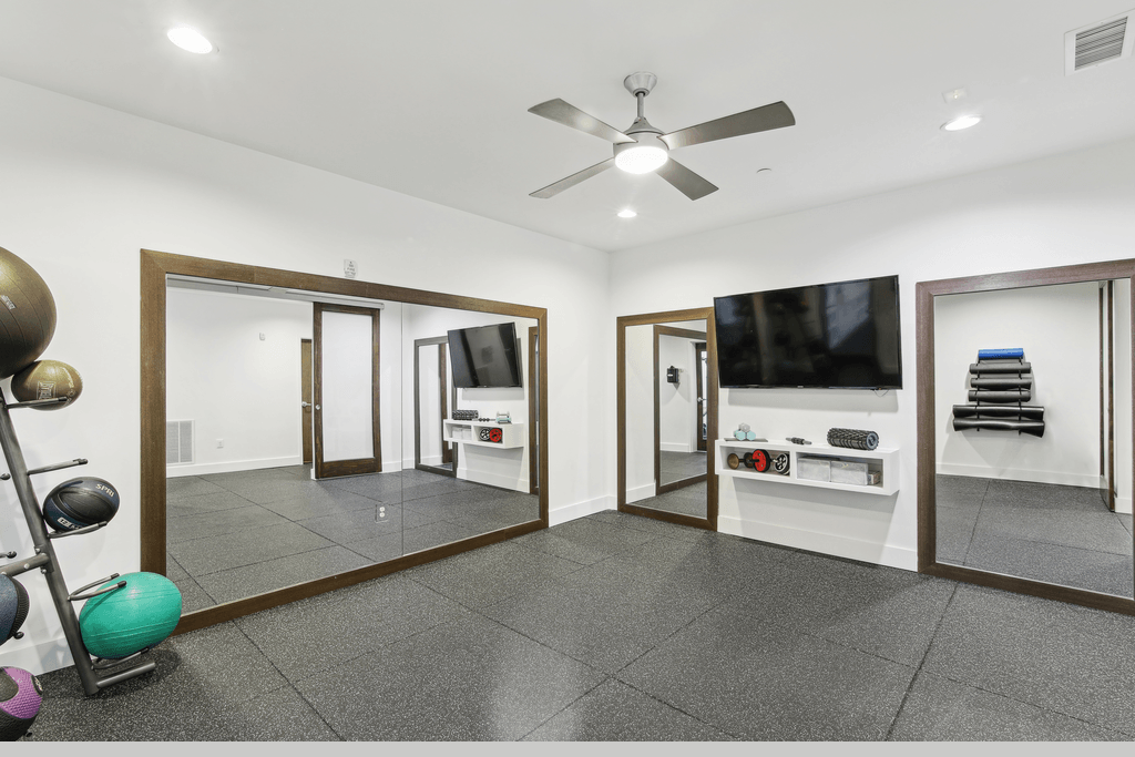 a living room with a ceiling fan and mirrors and a tv