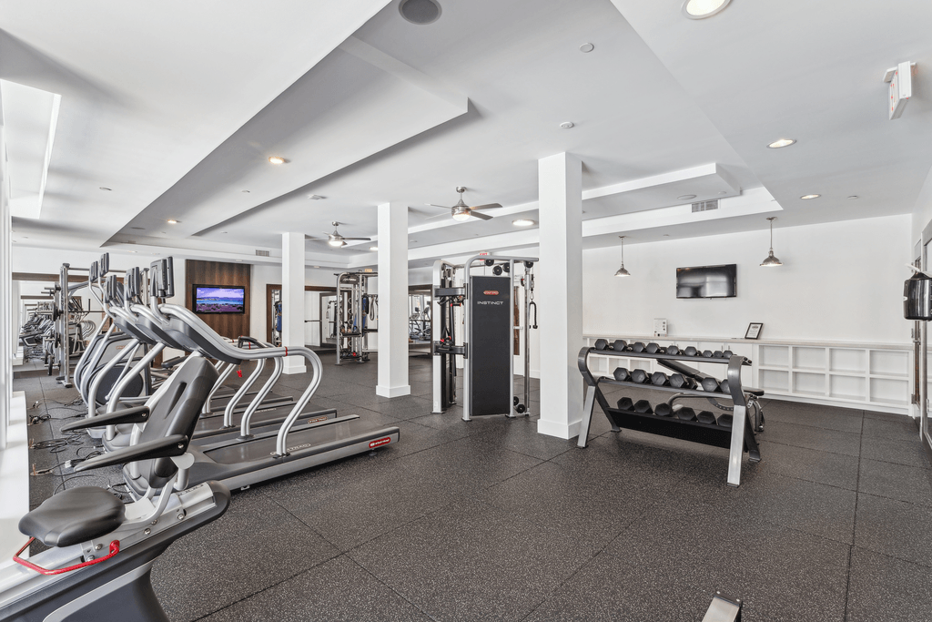 a gym with cardio equipment and weights in a building with white walls