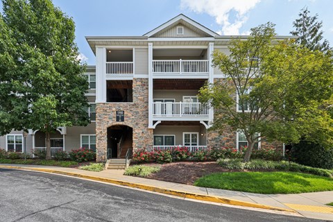 A two-story apartment building with a stone facade and a balcony on the second floor.