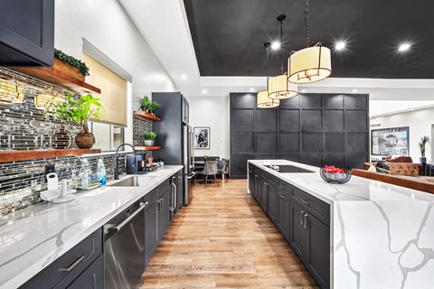 A modern kitchen with dark cabinets and a wooden floor.