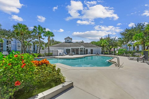Pool area with tanning chairs on the deck surrounded by natural landscaping