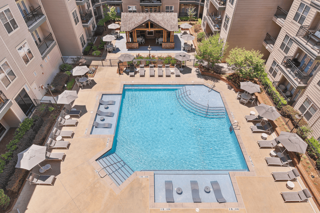 an overhead view of an apartment pool with chairs and umbrellas