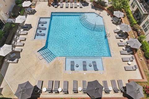 An aerial view of a swimming pool surrounded by lounge chairs and umbrellas.
