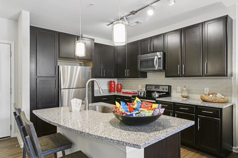 A kitchen with black cabinets and a granite countertop.