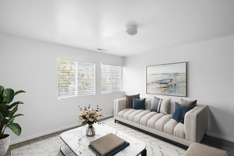 A living room with a couch, coffee table, and a painting on the wall.