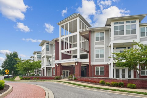 A modern apartment building with a red brick base and white upper floors.