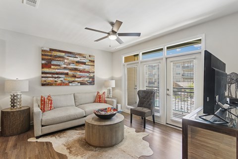 A living room with a grey couch, a wooden coffee table, a flat screen TV and a painting on the wall.