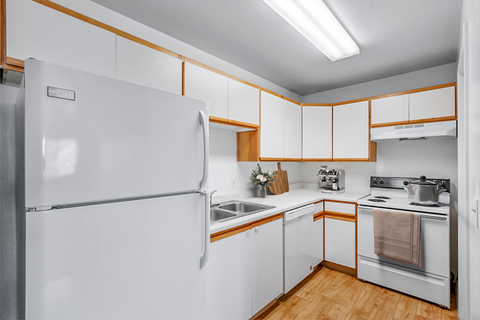 A white refrigerator is in a kitchen with wooden cabinets.