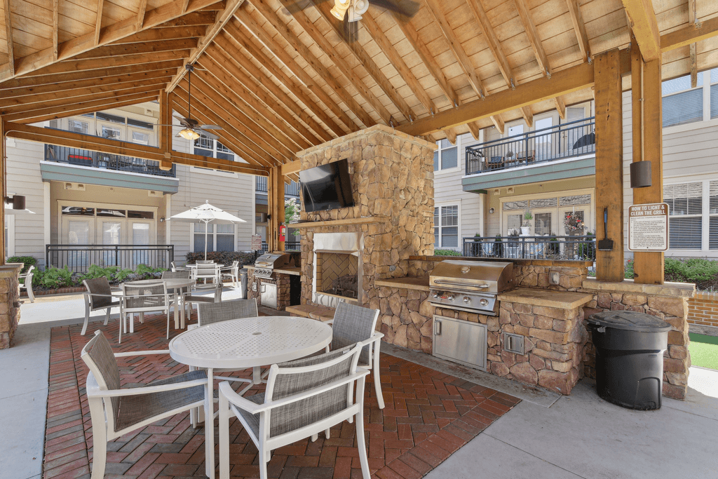 a covered patio with a stone fireplace and tables and chairs