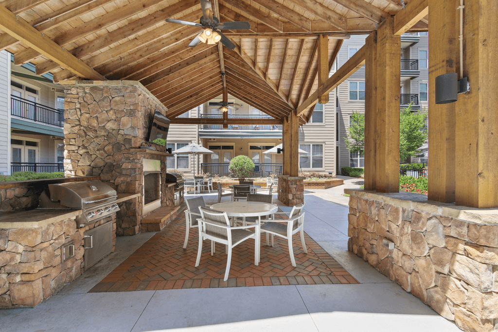a patio with a table and chairs and a grill