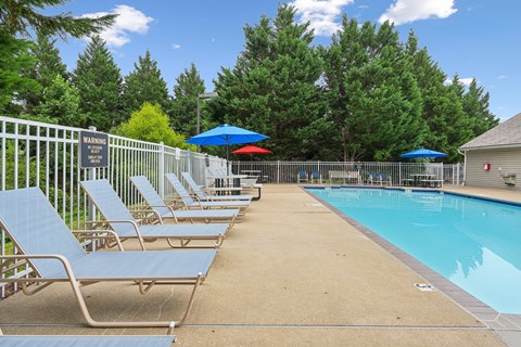 A pool area with sun loungers and a warning sign.