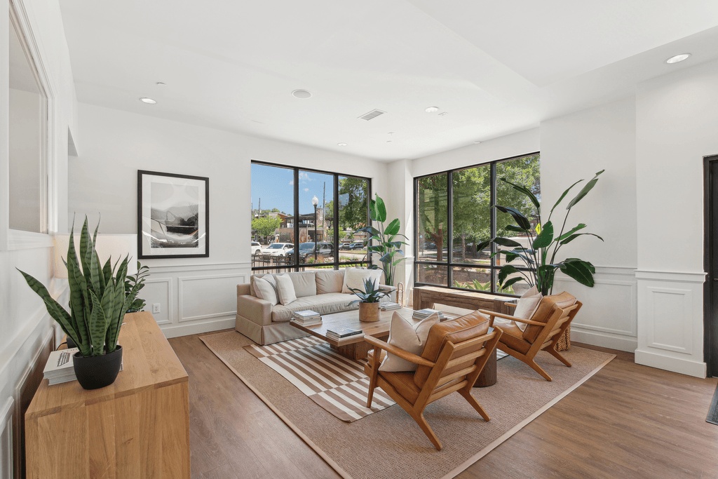 a living room with a couch and chairs and large windows