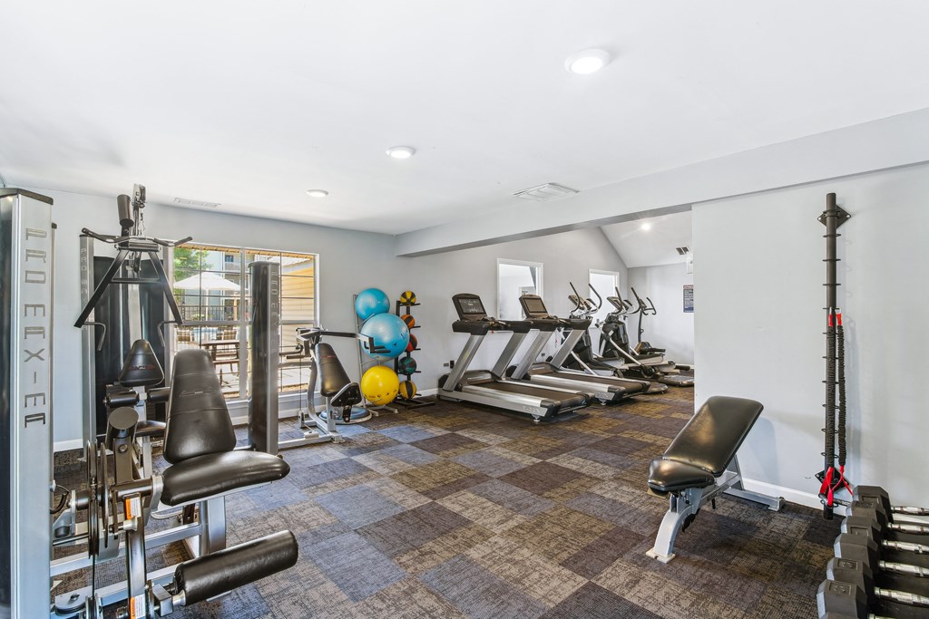 a gym with cardio equipment and weights on a checkered floor