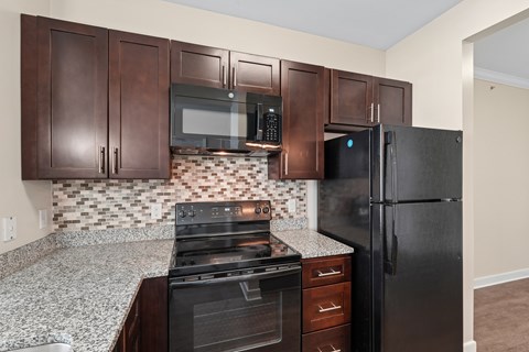 A kitchen with brown cabinets and a black refrigerator.