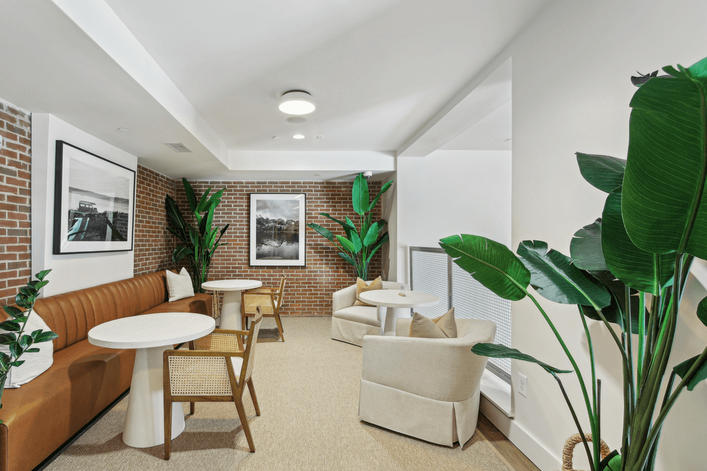 a living room with couches chairs and tables and a brick wall