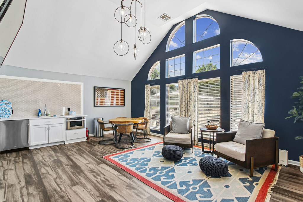 a living room with a large window and a kitchen with a table and chairs