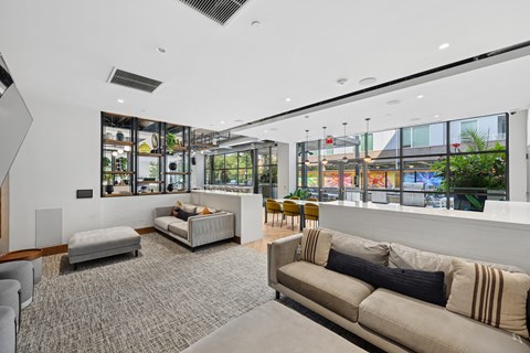 A modern living room with a grey carpet and a large window.
