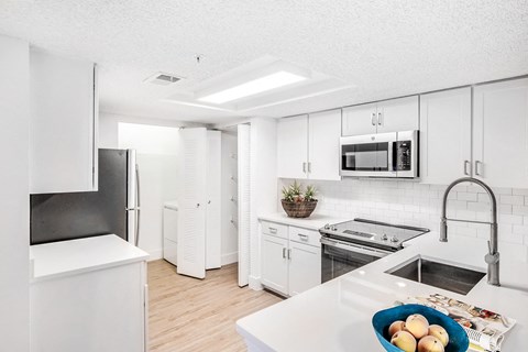 A kitchen with white appliances and cabinets.