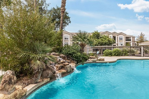 Swimming pool with cascading waterfall and lush greenery at Tierra Antigua Apartments, Mesa, AZ 85207