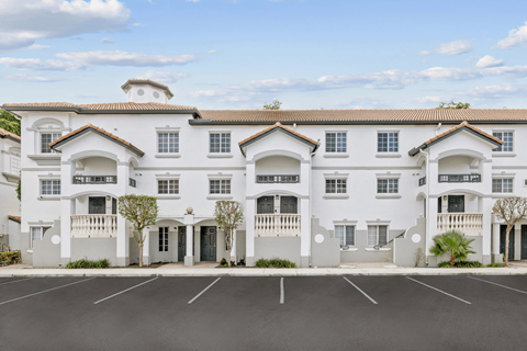 a large white building with balconies and a parking lot