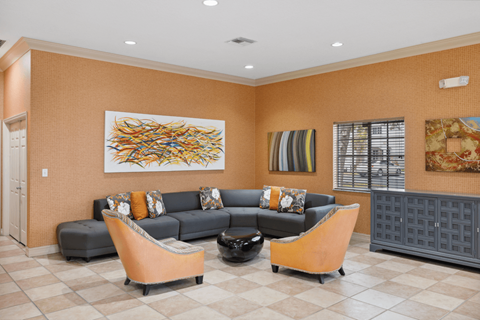 A living room with a grey couch and orange chairs.