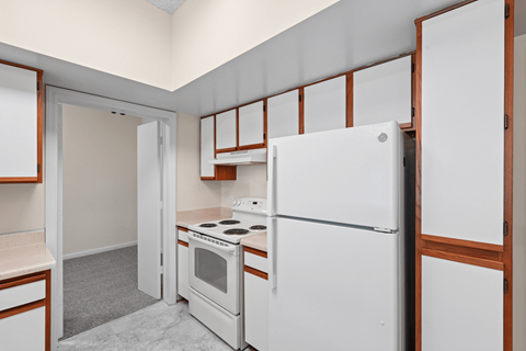 A white refrigerator is in a kitchen with a white oven and wooden cabinets.