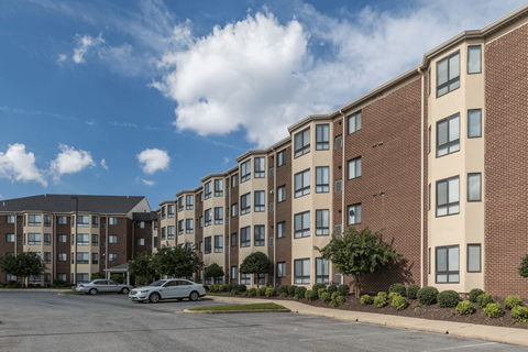 A large brick apartment building with a parking lot in front.
