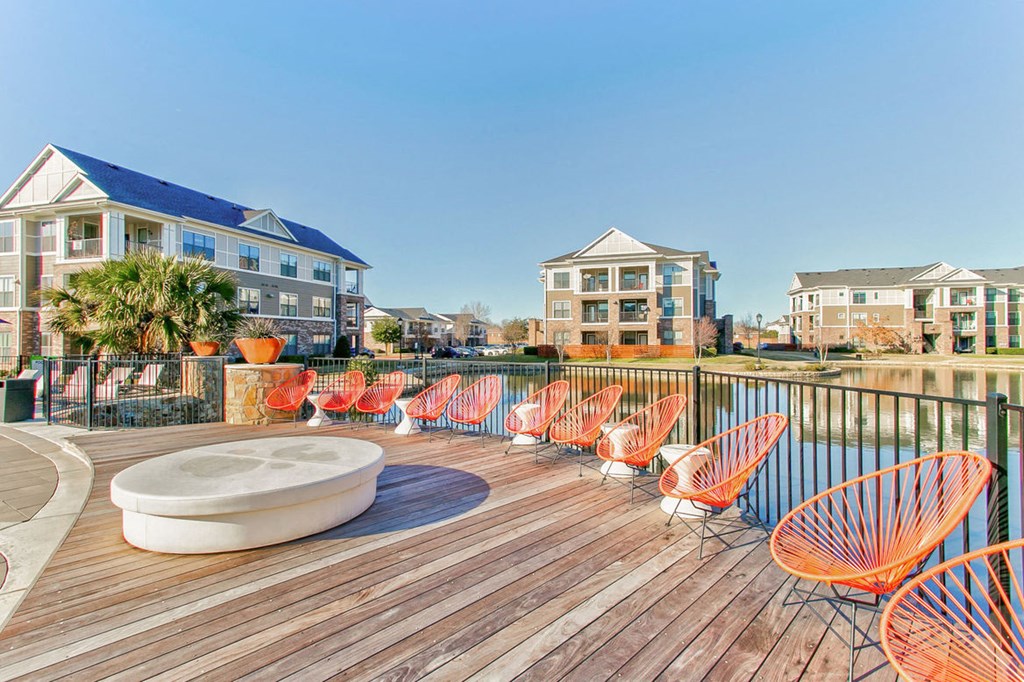 wooden deck with lounge chairs and pond in background