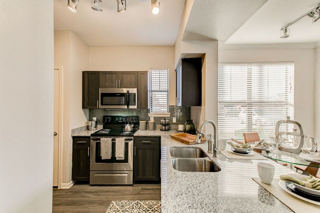 a kitchen with a large window and a granite-style countertops