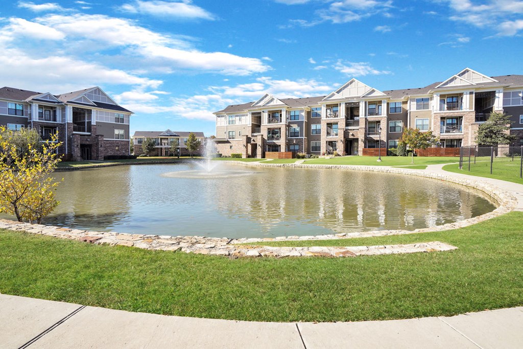 pond with fountain with apartment buildings in the background