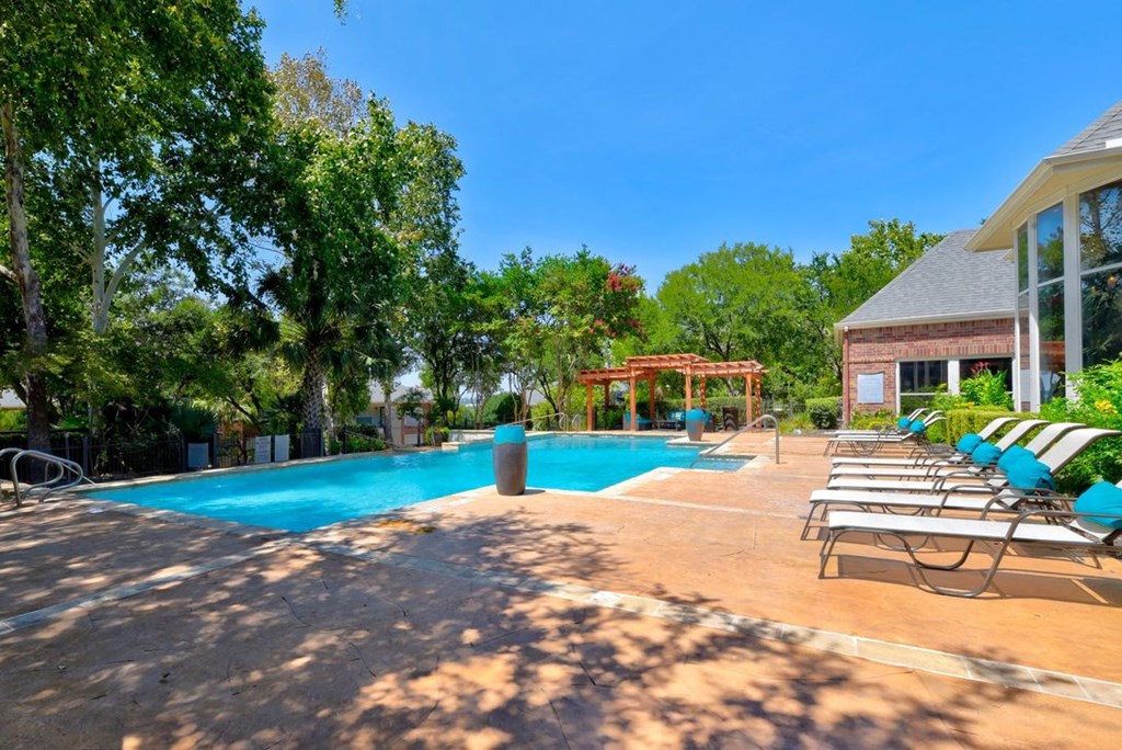 Pool area with lounge chairs and tables surrounding pool