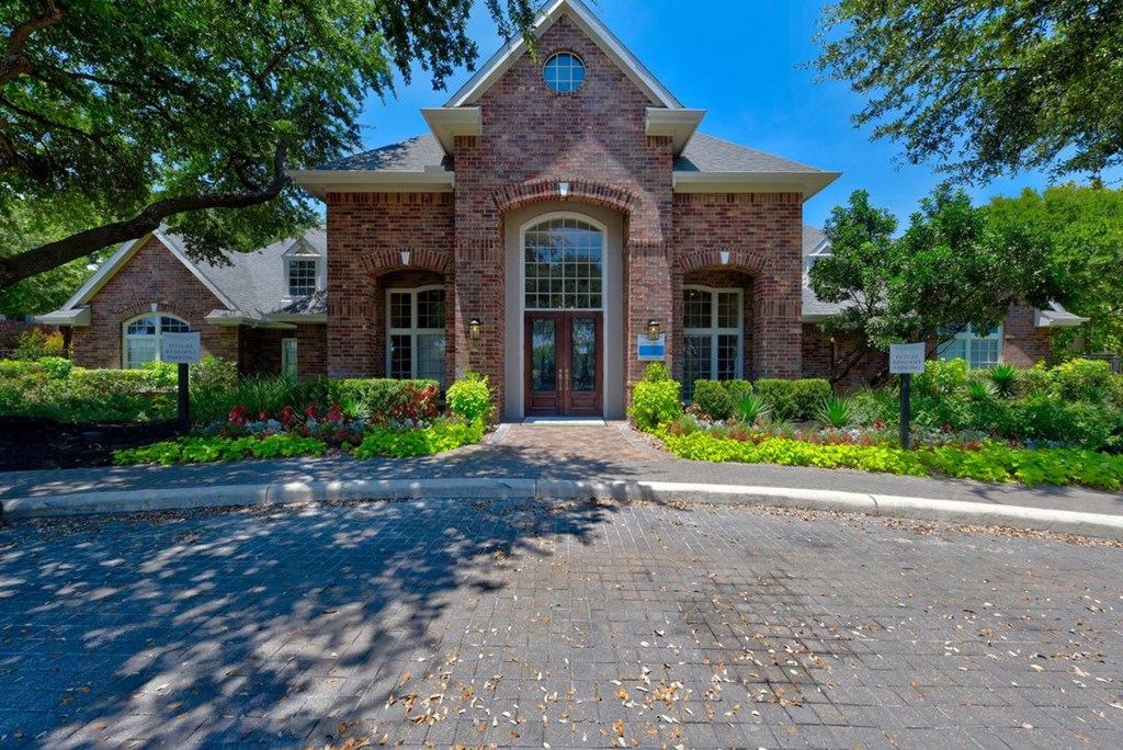 a leasing office with a driveway and trees in front of it
