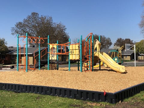 A playground with a yellow slide and a green and orange structure.
