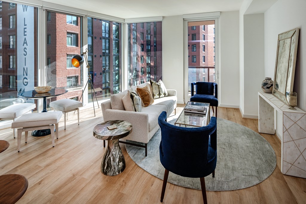 a living room with a couch and chairs and large windows