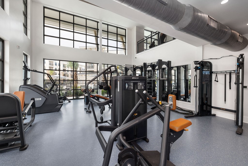 a gym with weights and cardio equipment in a building with windows