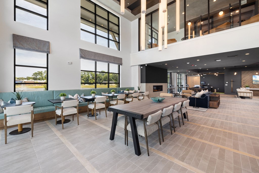 a dining room with a long table and chairs in a building with large windows